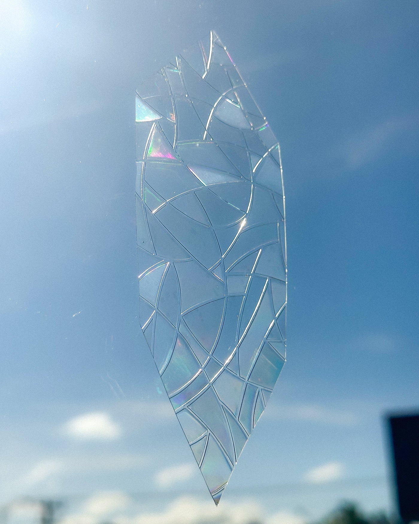Decorative glass panel with geometric pattern against a blue sky